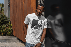 Man wearing a white t-shirt with a graphic design, MLK- Martin Luther King Jr. "I have a Dream" standing outdoors.