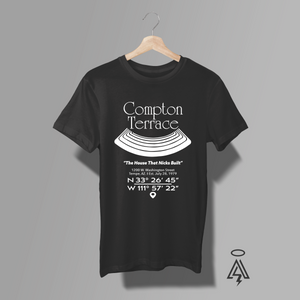 A black short-sleeve t-shirt. The shirt features a white graphic print on the front with the text 'Compton Terrace' and coordinates, along with a stylized concert lawn design.