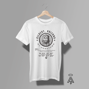 White t-shirt with black graphic design, paying homage to Gilbert, Arizona stating "My Hometown" with cool water tower graphic with coordinates elow it.
