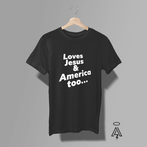 A black short-sleeve t-shirt. The shirt features the text 'Loves Jesus & America too.