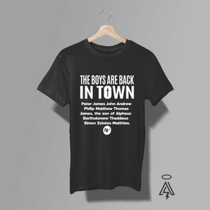 A black short-sleeve graphic T-shirt. The shirt features white text reading 'THE BOYS ARE BACK IN TOWN' followed by a list of the Disciples.