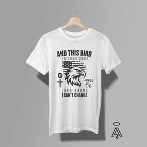 A white short-sleeve t-shirt, The shirt features a black graphic print of an eagle head, a cross, a US flag, and the text 'AND THIS BIRD YOU CANNOT CHANGE .
